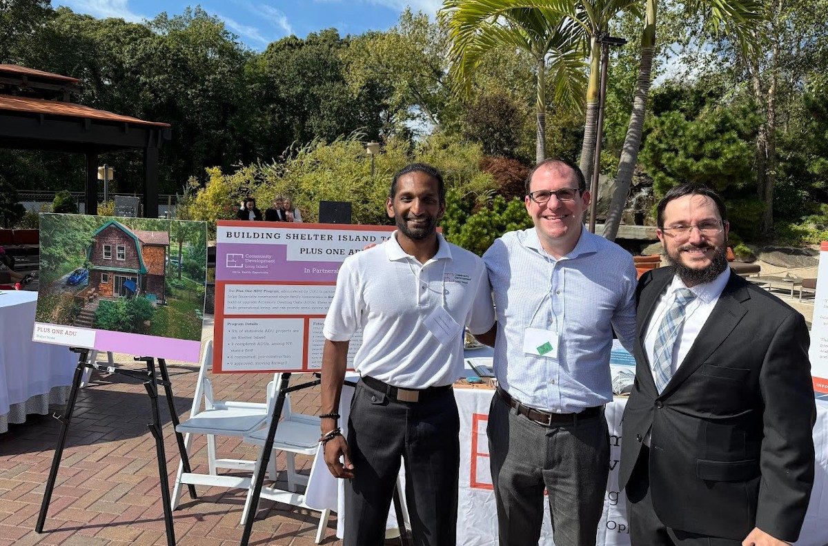 Blue Engine Solutions team members at a CDLI event next to a display about the Plus One ADU program