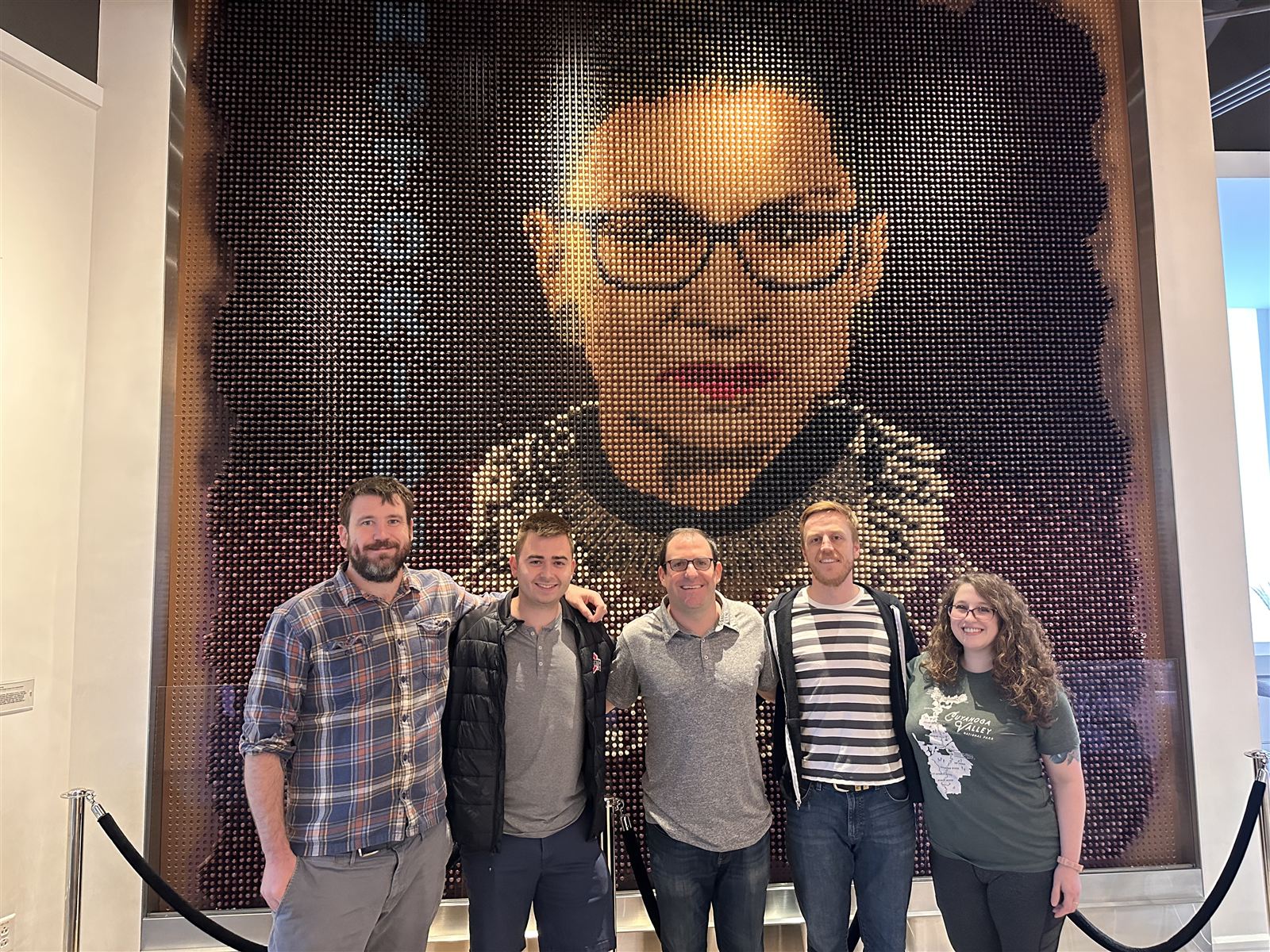 The Blue Engine Solutions team in front of a large mosaic portrait in Washington, DC
